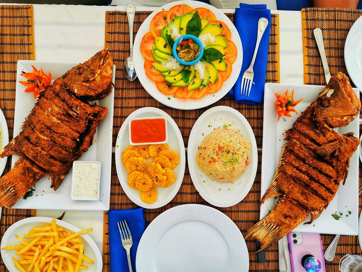 Illustrative Caribbean-inspired table with whole fish, rice, and vegetables
